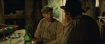 Movie still from “Jean de Florette” (1986), directed by Claude Berri – A man wearing a hat talking to another man in front of a window; Medium shot, Over the shoulder angle