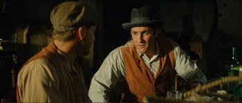 Movie still from “Jean de Florette” (1986), directed by Claude Berri – A man wearing a hat and vest talking to another man; Medium shot, Over the shoulder angle