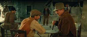 Movie still from “Jean de Florette” (1986), directed by Claude Berri – Two men sitting at a table in front of a building; Medium shot, Over the shoulder angle