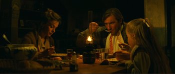 Movie still from “Jean de Florette” (1986), directed by Claude Berri – A group of people sitting at a table with a candle; Medium shot, Low angle