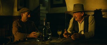 Movie still from “Jean de Florette” (1986), directed by Claude Berri – Two men sitting at a table with wine glasses; Medium shot, Low angle