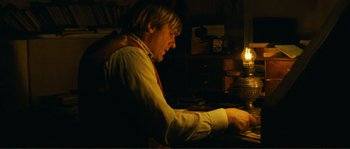 Movie still from “Jean de Florette” (1986), directed by Claude Berri – A man sitting at a desk in front of a computer; Medium shot, High angle