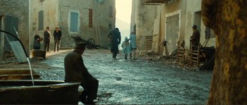 Movie still from “Jean de Florette” (1986), directed by Claude Berri – A group of people walking down a street near a building; Wide shot, High angle