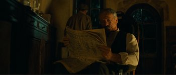 Movie still from “Jean de Florette” (1986), directed by Claude Berri – An older man sitting down reading a newspaper; Medium shot, Low angle