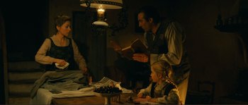 Movie still from “Jean de Florette” (1986), directed by Claude Berri – A man and a little girl sitting at a table reading a book; Medium shot, High angle