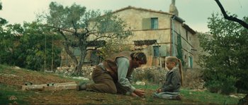Movie still from “Jean de Florette” (1986), directed by Claude Berri – A man kneeling on the ground next to a little girl; Wide shot, Low angle