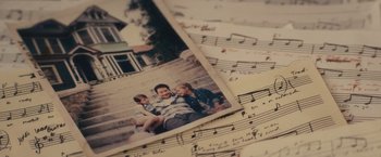 Movie still from “Jem and the Holograms” (2015), directed by Jon M. Chu – An old photo of a man holding a young boy and a sheet of music; Extreme Close Up shot, Overhead angle