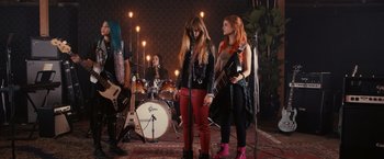 Movie still from “Jem and the Holograms” (2015), directed by Jon M. Chu – A group of young women standing next to each other in a room; Wide shot, Low angle