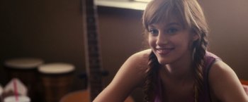 Movie still from “Jem and the Holograms” (2015), directed by Jon M. Chu – A woman with a braid is smiling for the camera; Close Up shot, Over the shoulder angle