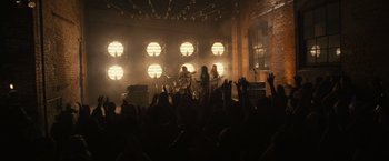 Movie still from “Jem and the Holograms” (2015), directed by Jon M. Chu – A group of people in front of a stage with lights on; Wide shot, Low angle
