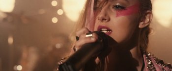 Movie still from “Jem and the Holograms” (2015), directed by Jon M. Chu – A woman holding a microphone up to her mouth; Close Up shot, Low angle
