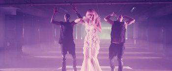 Movie still from “Jem and the Holograms” (2015), directed by Jon M. Chu – A woman in a white dress singing into a microphone; Wide shot, Low angle