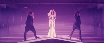 Movie still from “Jem and the Holograms” (2015), directed by Jon M. Chu – A woman standing on a stage in front of a microphone; Wide shot, High angle