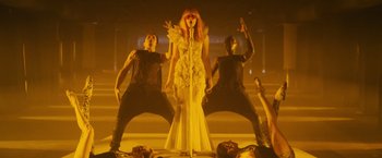 Movie still from “Jem and the Holograms” (2015), directed by Jon M. Chu – A woman standing on top of a stage next to two men; Wide shot, Low angle