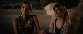 Movie still from “Jem and the Holograms” (2015), directed by Jon M. Chu – Two young women holding hands while standing next to each other; Medium shot, Over the shoulder angle