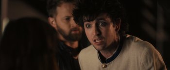 Movie still from “Jem and the Holograms” (2015), directed by Jon M. Chu – A man standing next to another man in a room; Close Up shot, Over the shoulder angle