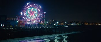 Movie still from “Jem and the Holograms” (2015), directed by Jon M. Chu – A ferris wheel lit up at night on a pier; Extreme Wide shot, High angle