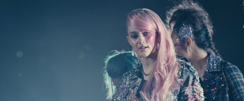 Movie still from “Jem and the Holograms” (2015), directed by Jon M. Chu – A woman with pink hair and pink eye shadow; Close Up shot, Over the shoulder angle