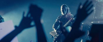 Movie still from “Jem and the Holograms” (2015), directed by Jon M. Chu – A person holding a guitar in front of a microphone; Medium shot, Low angle