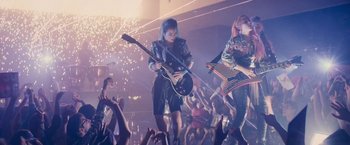 Movie still from “Jem and the Holograms” (2015), directed by Jon M. Chu – A group of young people playing guitar in front of a crowd; Wide shot, Low angle