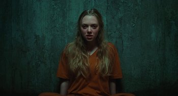 Movie still from “Jennifer's Body” (2009), directed by Karyn Kusama – A woman in an orange shirt is sitting in a chair; Medium shot, Overhead angle