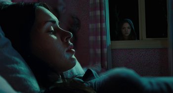 Movie still from “Jennifer's Body” (2009), directed by Karyn Kusama – A woman is laying in a bed with her eyes closed; Medium shot, Over the shoulder angle
