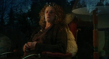 Movie still from “Jennifer's Body” (2009), directed by Karyn Kusama – An older woman sitting in a chair next to a lamp; Medium shot, Low angle