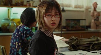 Movie still from “Jennifer's Body” (2009), directed by Karyn Kusama – A young woman wearing red glasses and a black shirt; Close Up shot, Over the shoulder angle