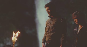 Movie still from “Jennifer's Body” (2009), directed by Karyn Kusama – A man standing in front of a wall with lights in the background; Medium shot, Over the shoulder angle