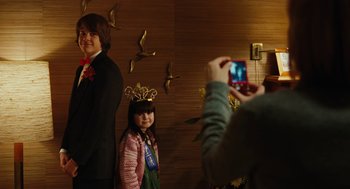 Movie still from “Jennifer's Body” (2009), directed by Karyn Kusama – A woman taking a picture of a man and a little girl; Medium shot, Over the shoulder angle