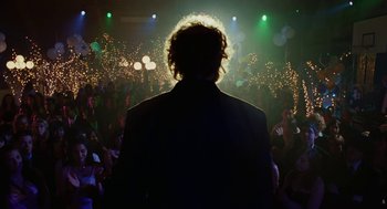 Movie still from “Jennifer's Body” (2009), directed by Karyn Kusama – A man standing in front of a crowd at a party; Medium shot, Low angle
