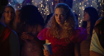 Movie still from “Jennifer's Body” (2009), directed by Karyn Kusama – A woman holding a cup in a room with lights; Close Up shot, Over the shoulder angle