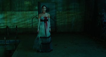 Movie still from “Jennifer's Body” (2009), directed by Karyn Kusama – A woman in a dress standing in a dark room; Wide shot, Low angle
