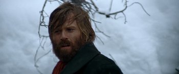 Movie still from “Jeremiah Johnson” (1972), directed by Sydney Pollack – A man with long hair and a beard standing next to a tree; Close Up shot, Low angle