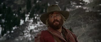 Movie still from “Jeremiah Johnson” (1972), directed by Sydney Pollack – A man with a beard wearing a hat and a scarf; Close Up shot, Low angle