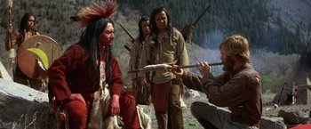 Movie still from “Jeremiah Johnson” (1972), directed by Sydney Pollack – A group of men in native american garb with arrows; Wide shot, Over the shoulder angle