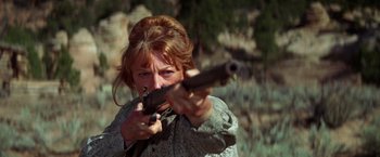 Movie still from “Jeremiah Johnson” (1972), directed by Sydney Pollack – A woman is holding a gun in her hands; Close Up shot, Low angle