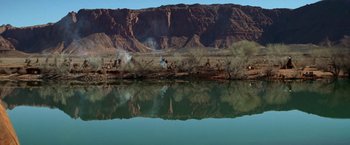Movie still from “Jeremiah Johnson” (1972), directed by Sydney Pollack – A body of water near a body of water with mountains in the background; Extreme Wide shot, High angle