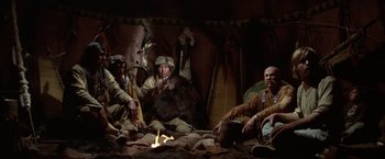 Movie still from “Jeremiah Johnson” (1972), directed by Sydney Pollack – A group of men sitting around a fire in a tent; Wide shot, Low angle