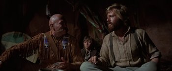 Movie still from “Jeremiah Johnson” (1972), directed by Sydney Pollack – Two men and a boy sitting in a room; Medium shot, Low angle