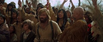 Movie still from “Jeremiah Johnson” (1972), directed by Sydney Pollack – A group of people standing in a forest with their hands raised; Medium shot, Over the shoulder angle