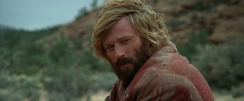Movie still from “Jeremiah Johnson” (1972), directed by Sydney Pollack – A man with long blonde hair wearing a blanket; Close Up shot, Low angle