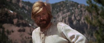 Movie still from “Jeremiah Johnson” (1972), directed by Sydney Pollack – A man with long hair and a beard is standing in front of a mountain; Close Up shot, Low angle