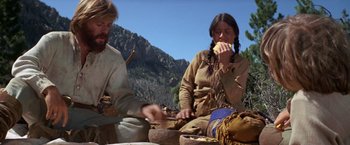 Movie still from “Jeremiah Johnson” (1972), directed by Sydney Pollack – A man and a woman sitting on the ground eating food; Medium shot, Low angle