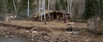 Movie still from “Jeremiah Johnson” (1972), directed by Sydney Pollack – A group of people standing around a log cabin; Extreme Wide shot, High angle