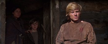 Movie still from “Jeremiah Johnson” (1972), directed by Sydney Pollack – A man and a boy standing next to each other in a room; Medium shot, Low angle
