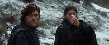 Movie still from “Jeremiah Johnson” (1972), directed by Sydney Pollack – Two people standing in the snow with one holding a piece of food; Close Up shot, Low angle