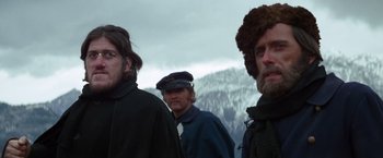 Movie still from “Jeremiah Johnson” (1972), directed by Sydney Pollack – A group of men standing next to each other in front of a mountain range; Close Up shot, Low angle