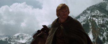 Movie still from “Jeremiah Johnson” (1972), directed by Sydney Pollack – A man with long blonde hair is standing next to a horse; Close Up shot, Low angle
