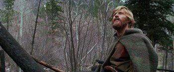 Movie still from “Jeremiah Johnson” (1972), directed by Sydney Pollack – A man with a beard and a green hair in the woods; Medium shot, Low angle